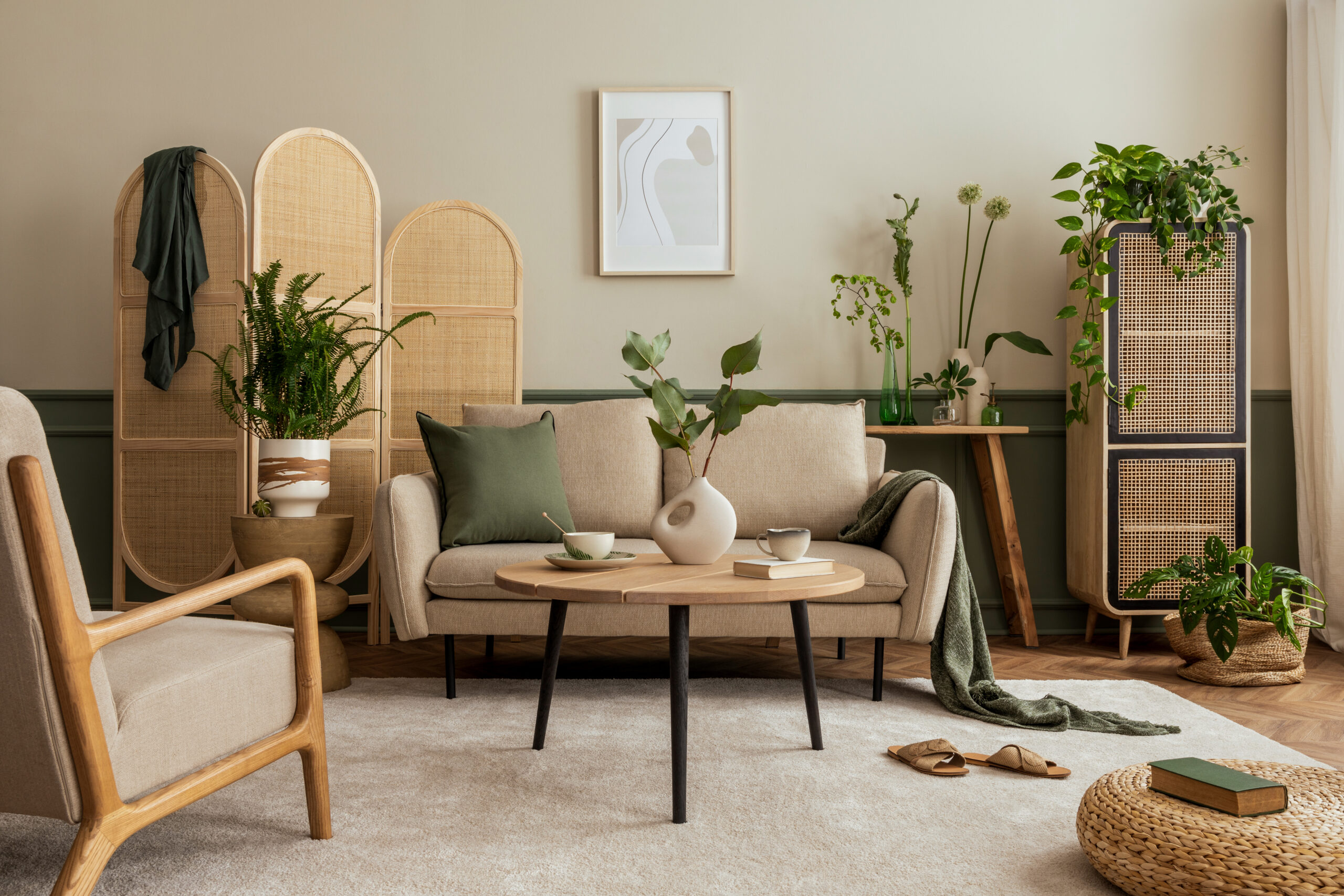 Creative composition of living room interior with beige sofa, wooden coffee table, rattan sideboard, partition wall, lamp, beige carpet, stylish armchair and personal accessories. Home decor. Template.